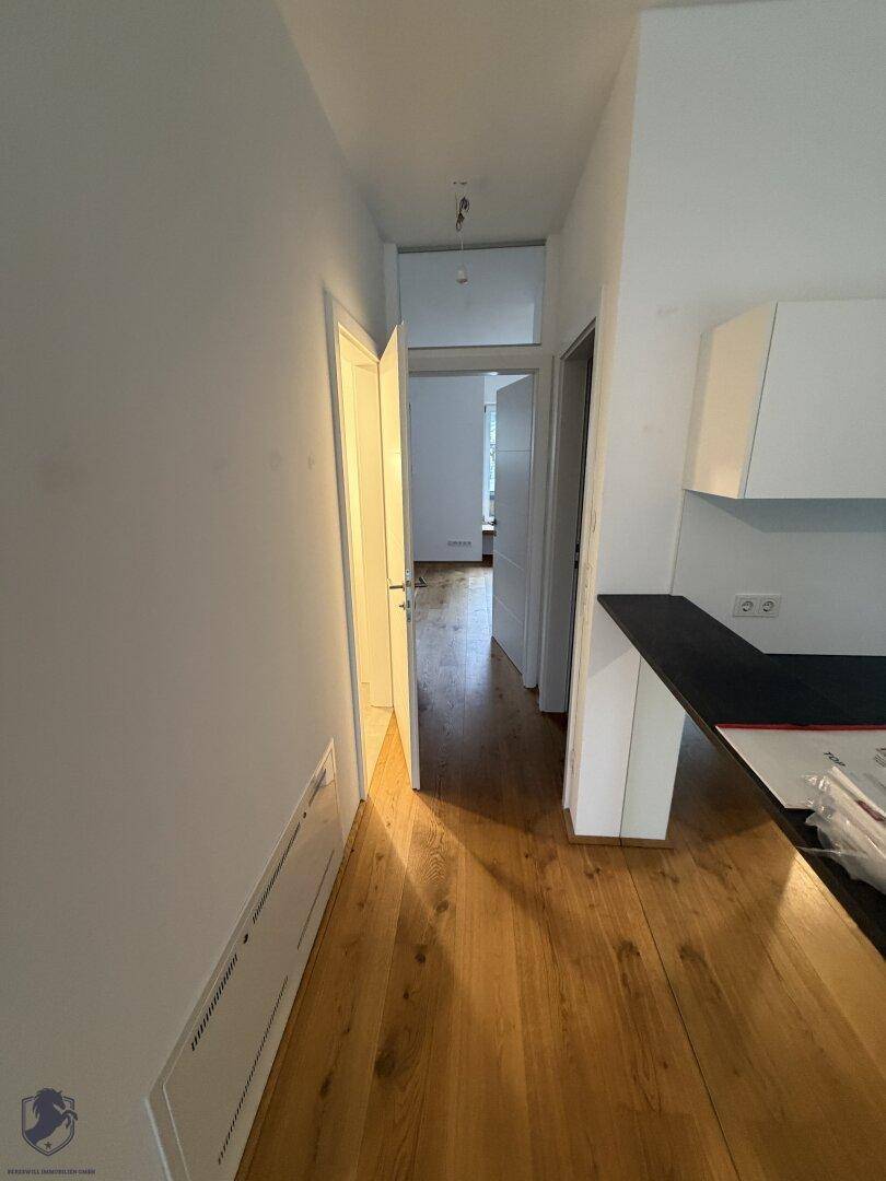 Heller Flur mit Holzboden, der zu den verschiedenen Räumen der Wohnung führt.