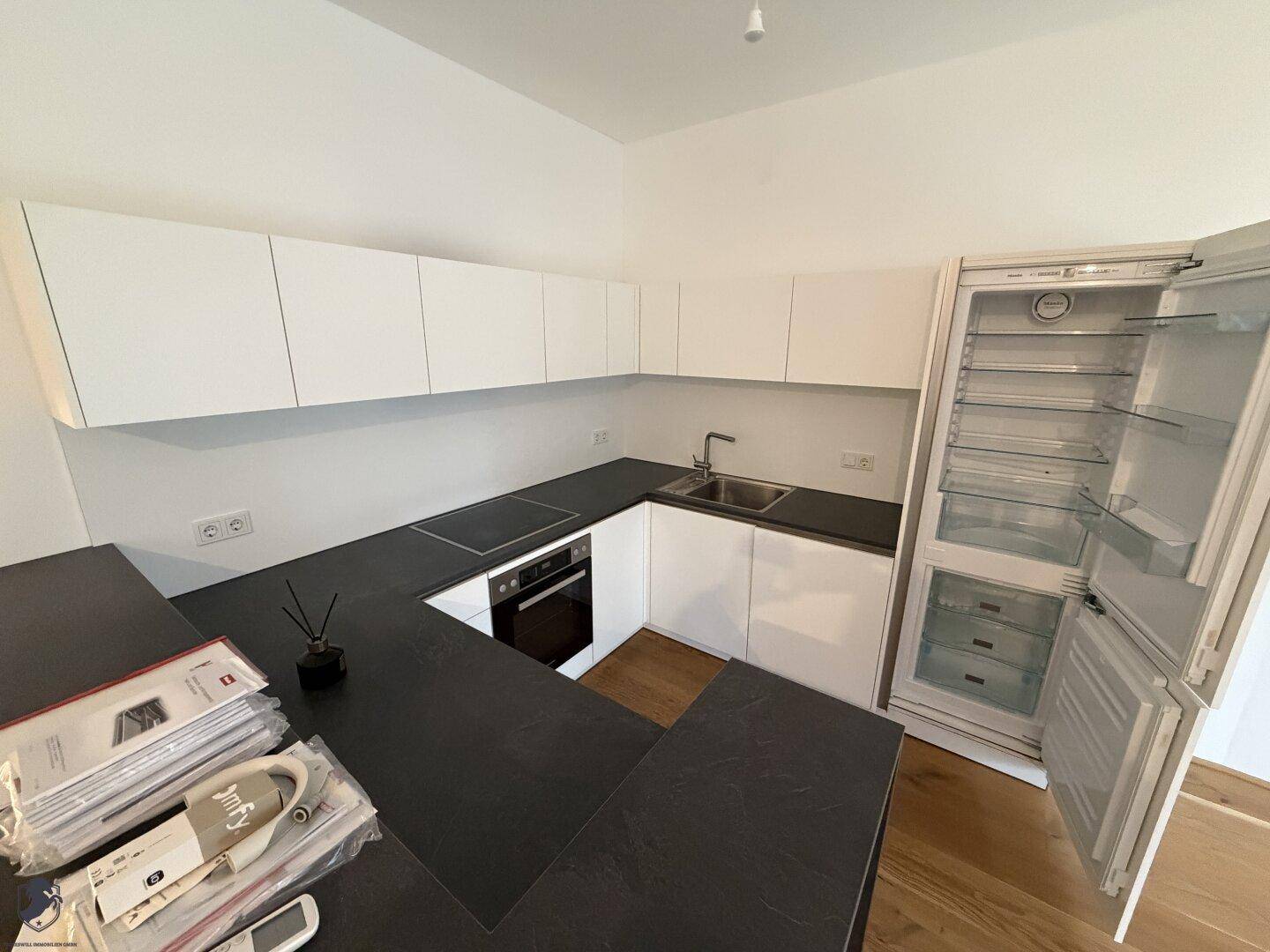 Voll ausgestattete moderne Küche mit Kühlschrank, Backofen und viel Stauraum.