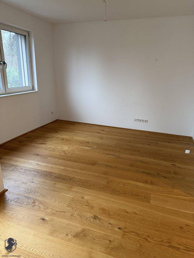 Helles und leeres Zimmer mit schönem Holzboden und weißen Wänden, vielseitig nutzbar.