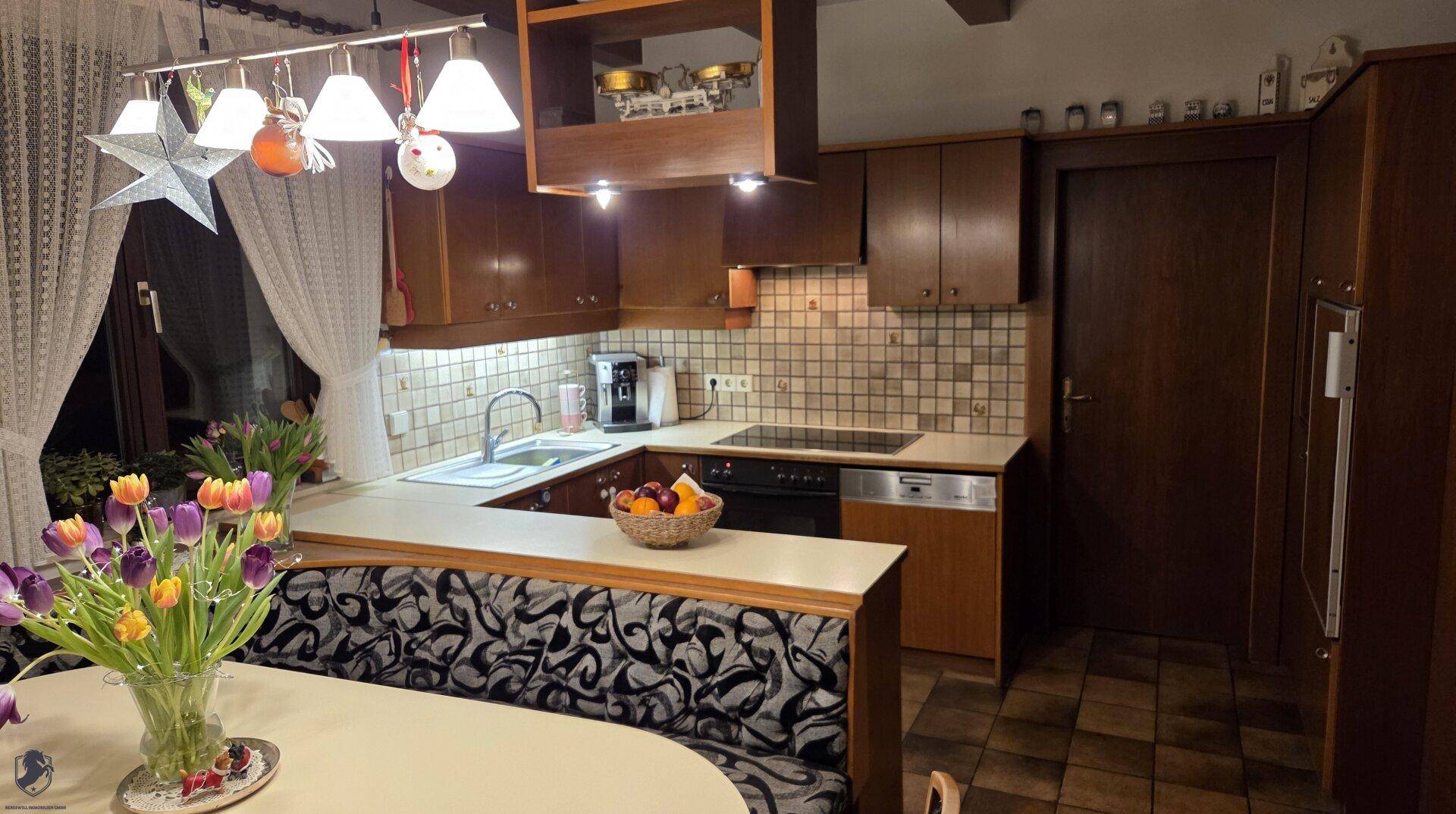 Gemütliche Küche mit dunklen Holzschränken, Fliesenspiegel und integriertem Essbereich mit Sitzbank.