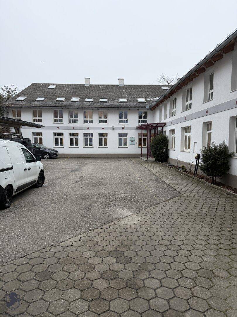 Weitläufiger gepflasterter Innenhof mit Parkmöglichkeiten und der Rückseite des Gebäudes.