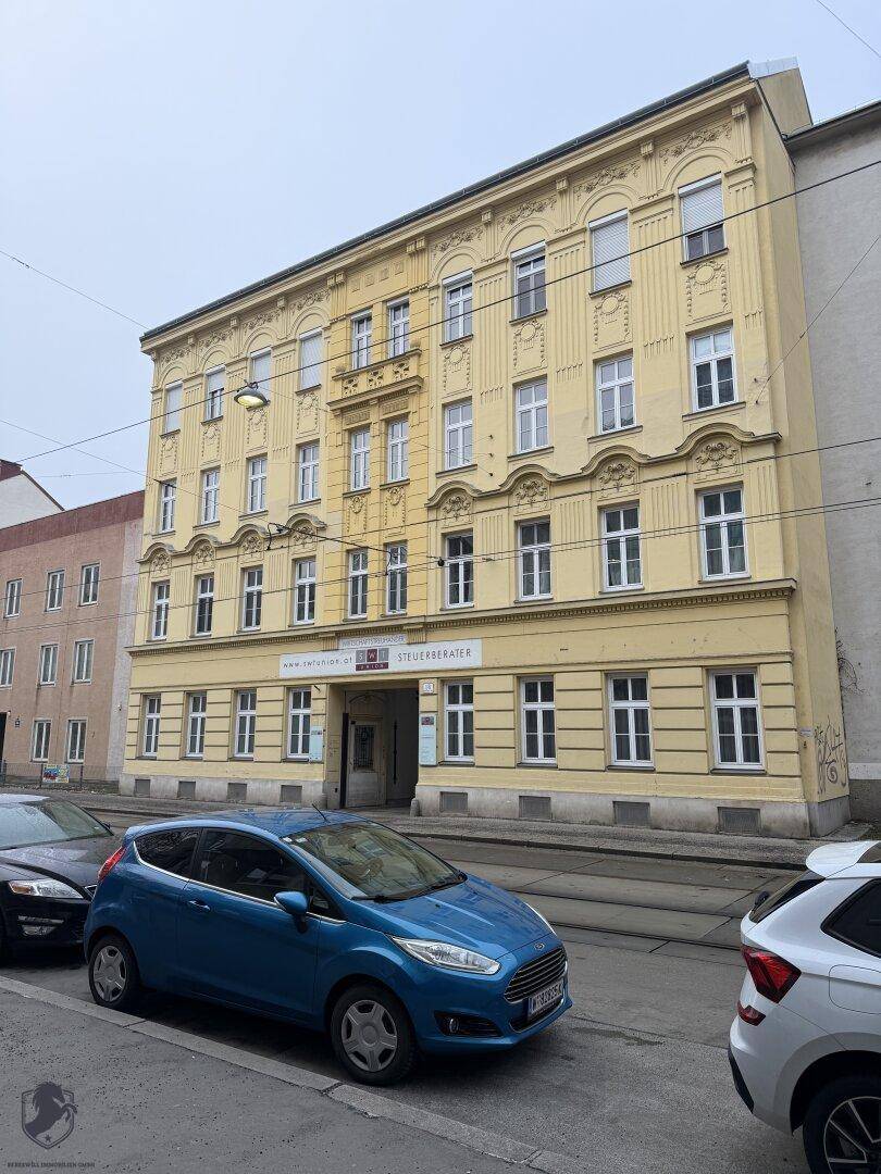 Historisches Gebäude mit gelber Fassade, vielen Fenstern und Blick auf die Straße.