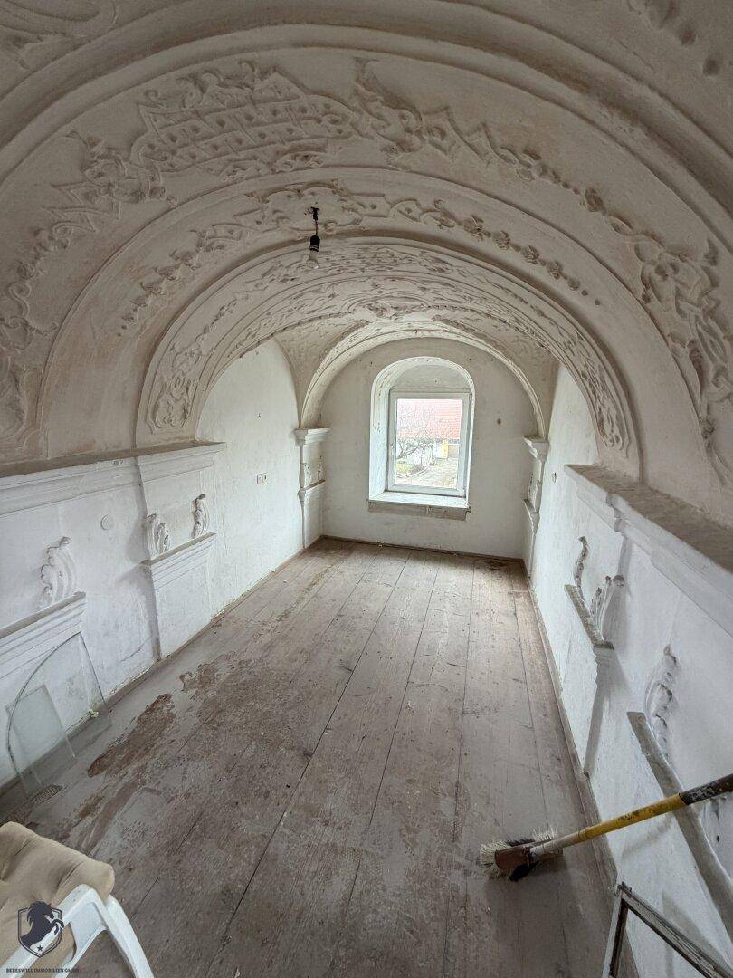 Historischer Raum mit beeindruckendem Gewölbe und aufwendigen Stuckverzierungen an der Decke.