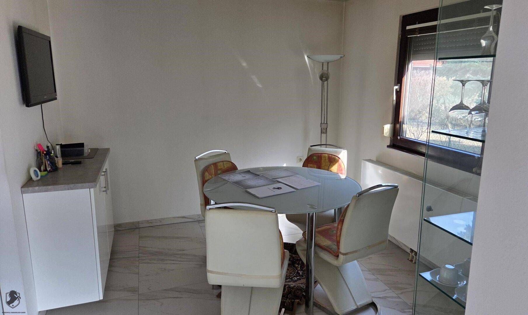 Essbereich mit rundem Tisch, vier Stühlen und einem Fenster.