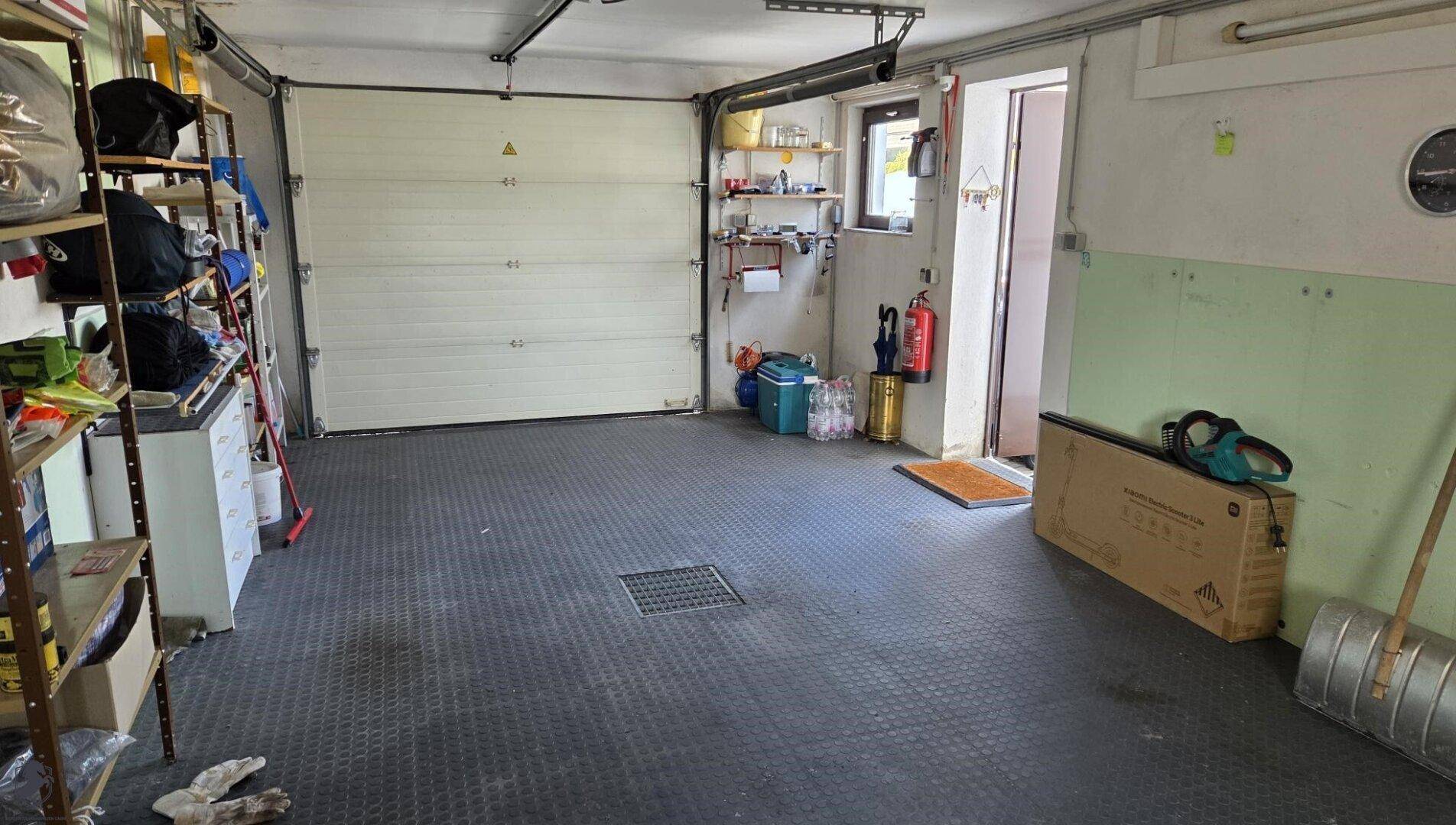 Große Garage mit Rolltor, Regalen und viel Stauraum.
