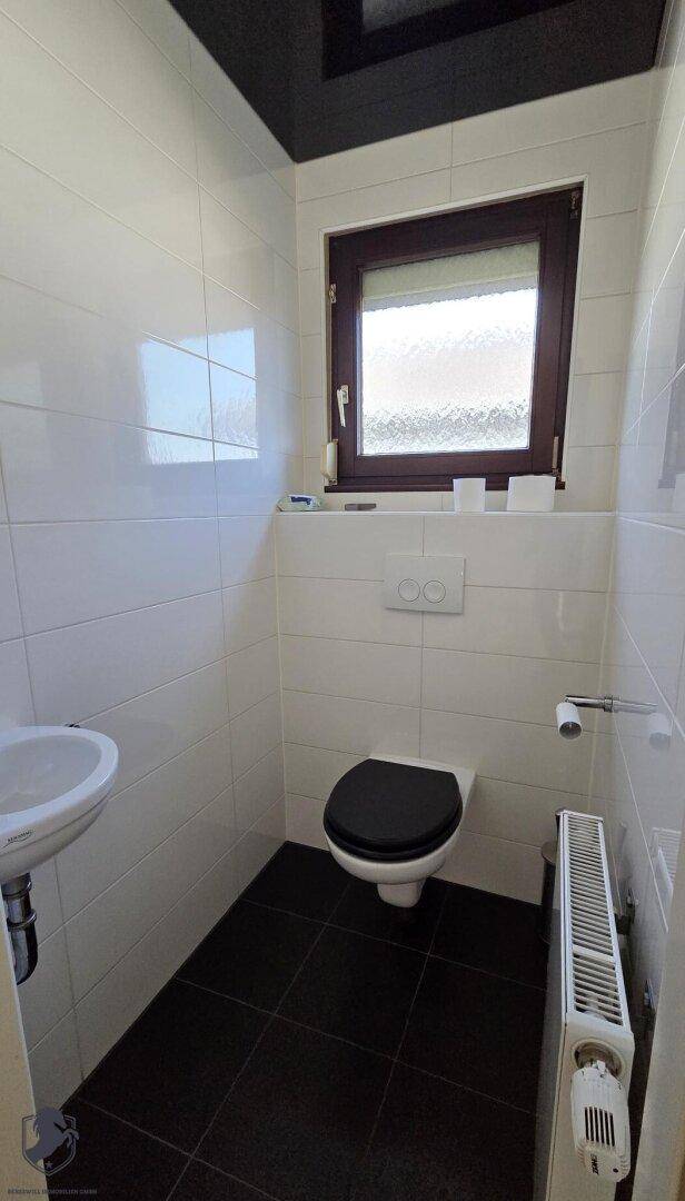 Kleines Gäste-WC mit Fenster, wandhängender Toilette und Waschbecken.