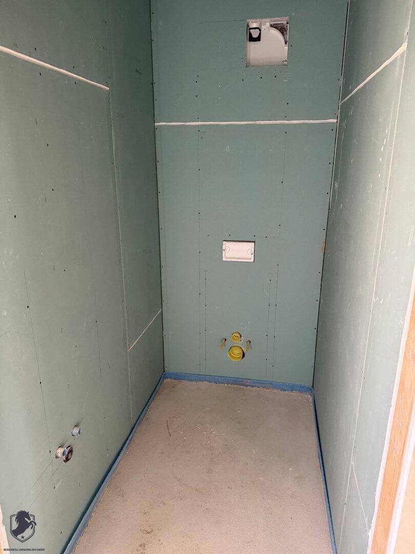 Badezimmer im Rohbau mit grünen Gipskartonplatten und vorbereiteten Anschlüssen.