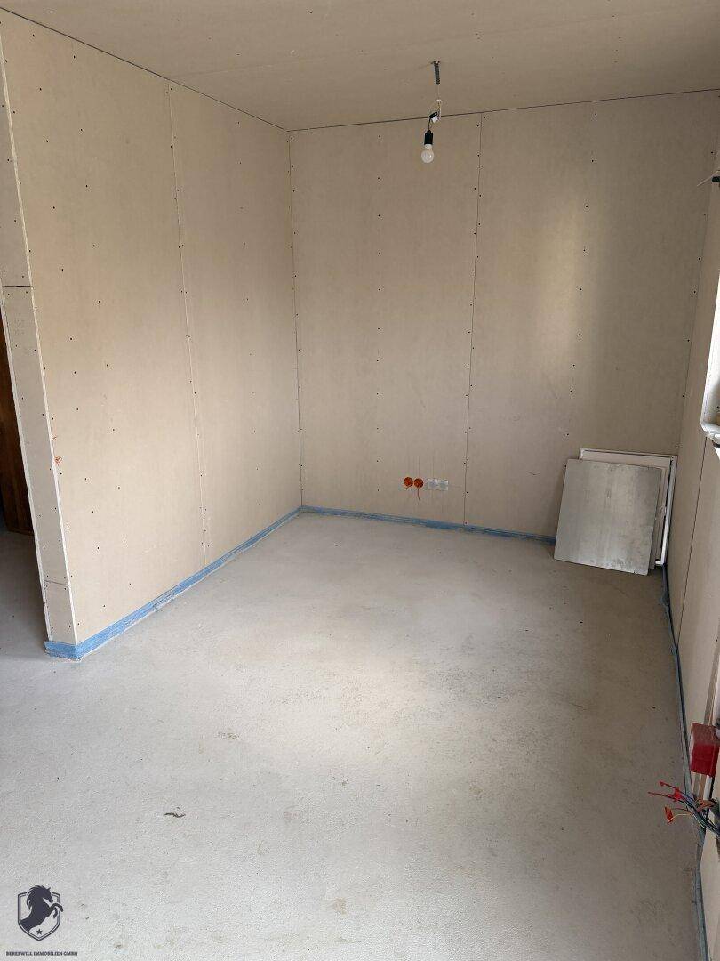 Schlafzimmer im Rohbau mit unfertigen Wänden und Betonboden.