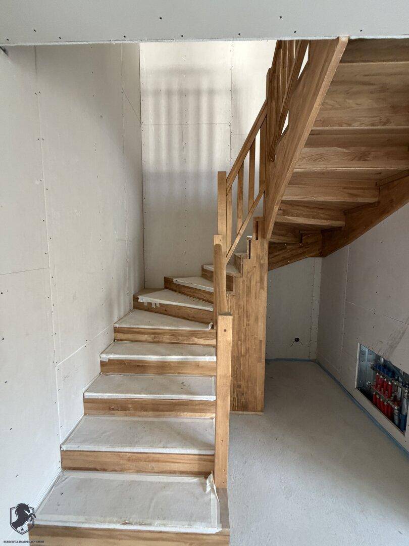 Holztreppe im Rohbau mit Schutzabdeckung auf den Stufen.