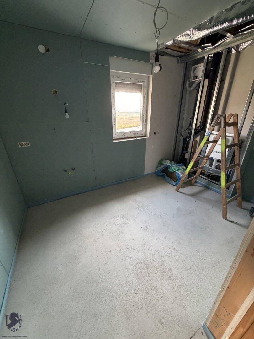 Zimmer im Rohbau mit grünen Gipskartonplatten und einem Fenster.