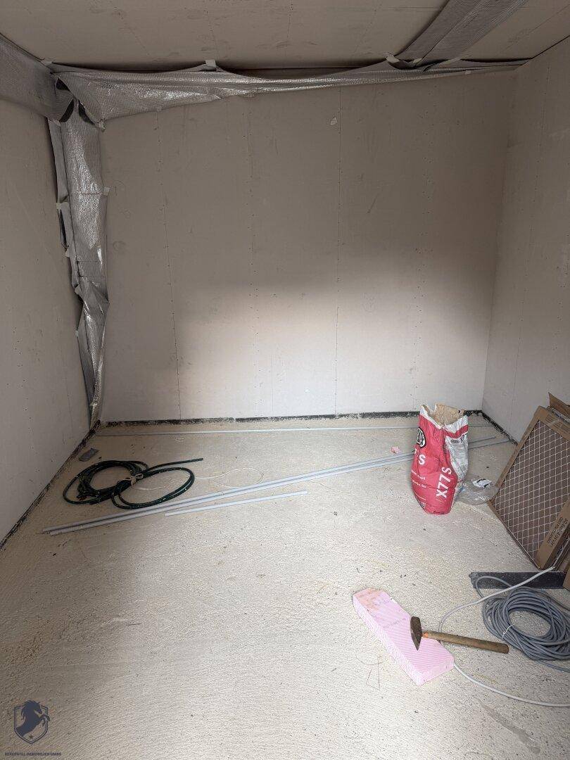 Kleiner Abstellraum im Rohbau mit Baumaterialien und unfertigen Wänden.