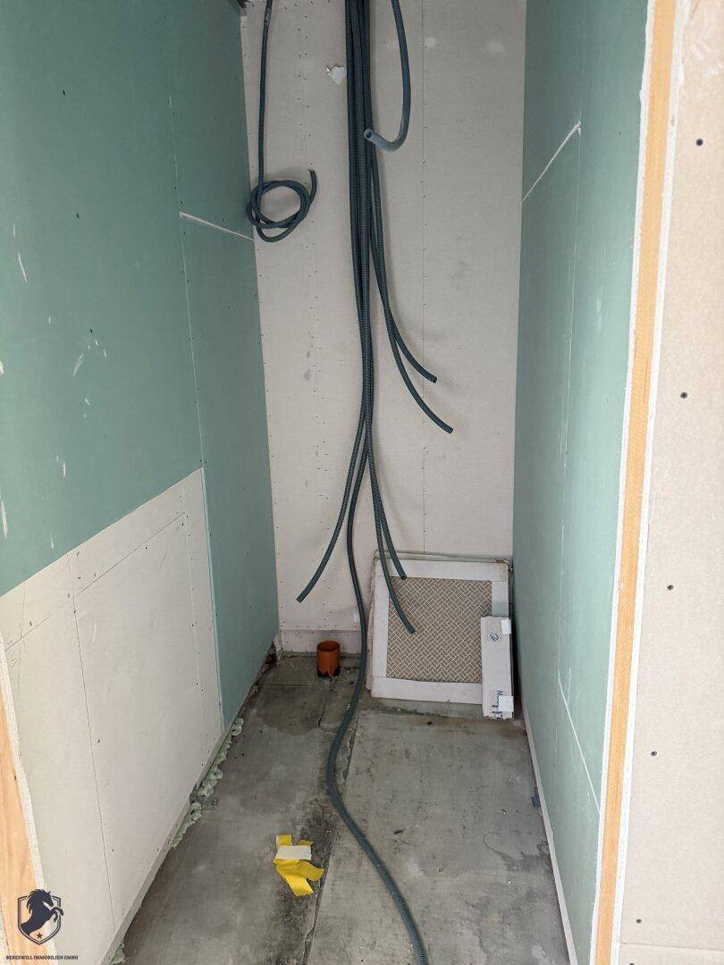 Kleiner Abstellraum im Rohbau mit sichtbaren Leitungen und unfertigen Wänden.