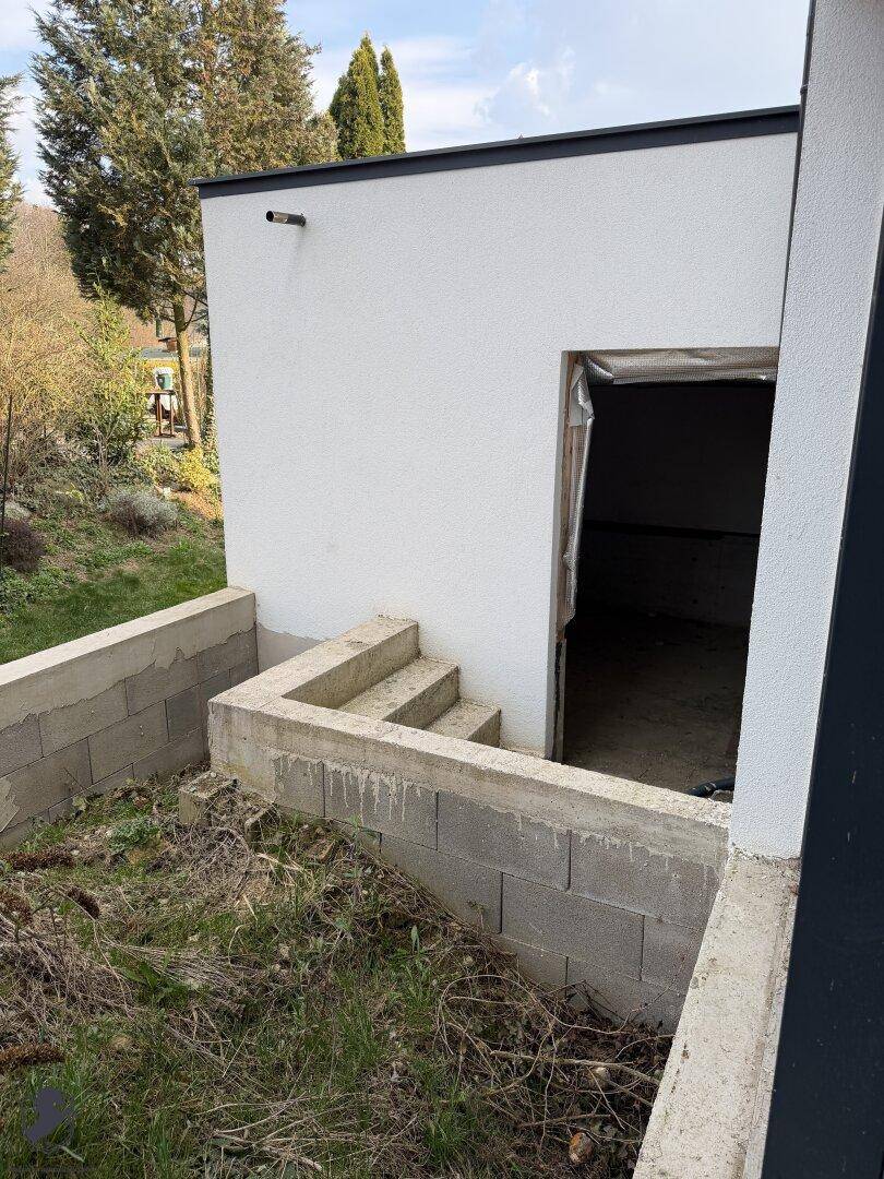 Unfertiger Außenbereich mit Betontreppe und unebenem Gelände.