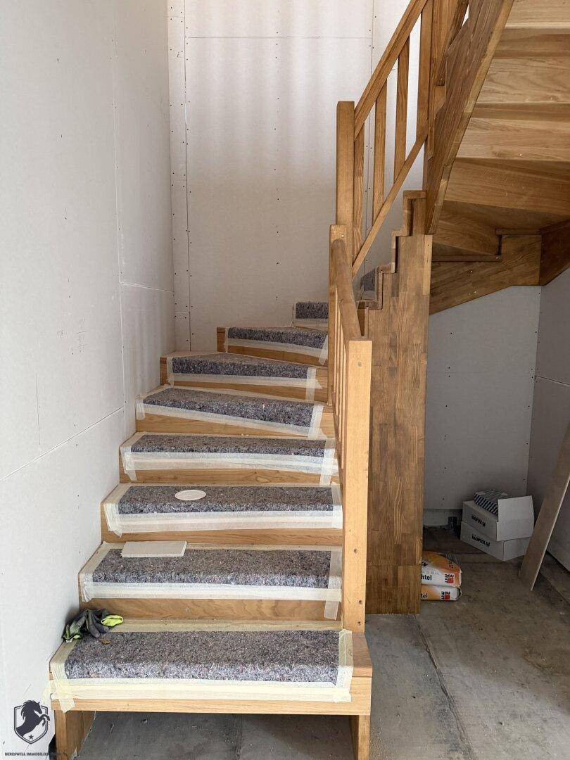 Holztreppe im Rohbau mit Schutzabdeckung auf den Stufen.