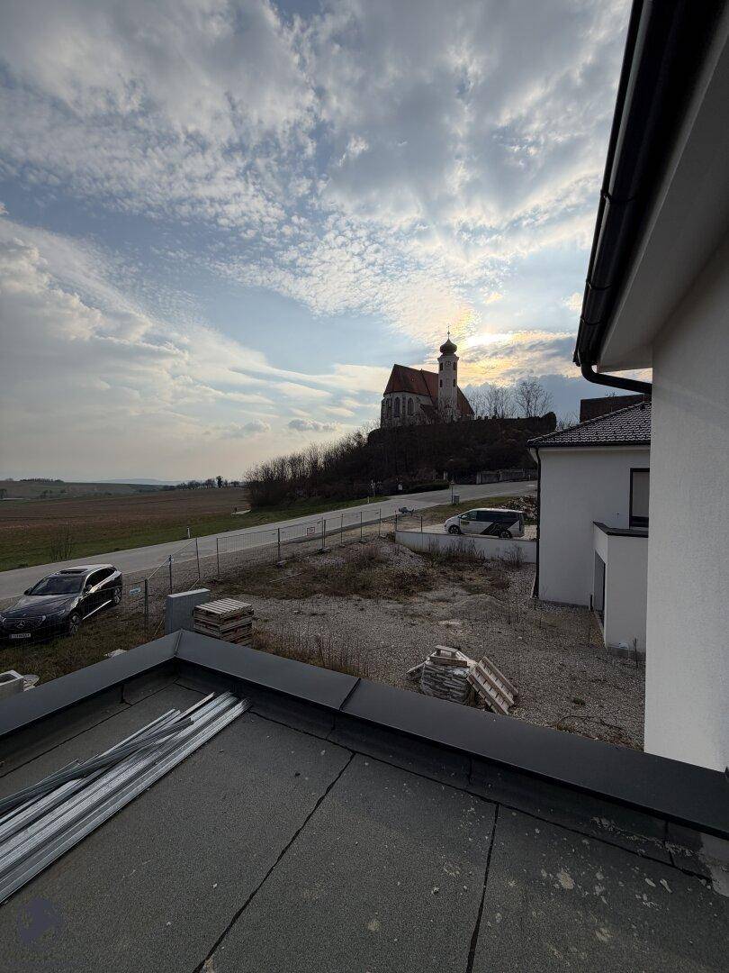 Panoramablick von einem Flachdach auf eine Kirche und die umliegende Landschaft.