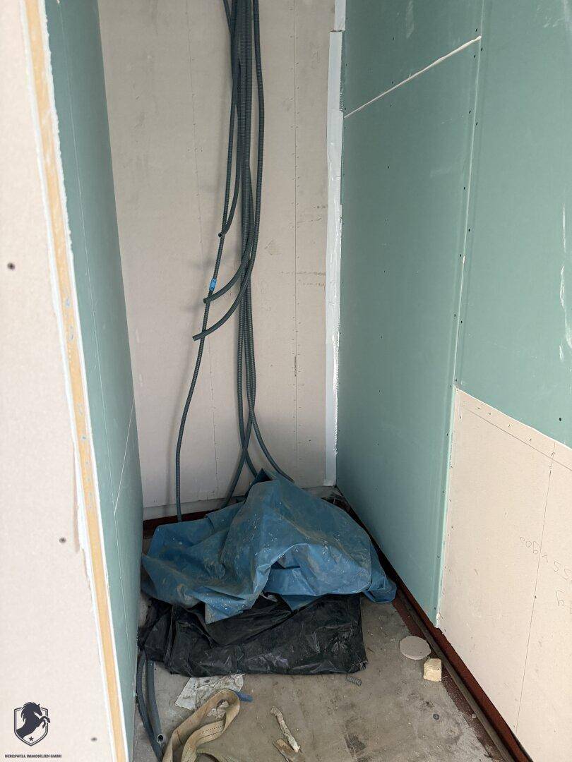 Kleiner Abstellraum im Rohbau mit sichtbaren Leitungen und unfertigen Wänden.