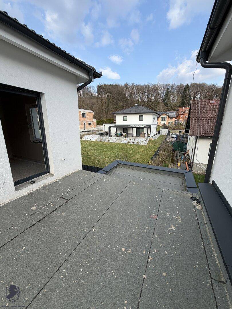 Blick von einem Flachdach auf benachbarte Häuser und einen gepflegten Garten.
