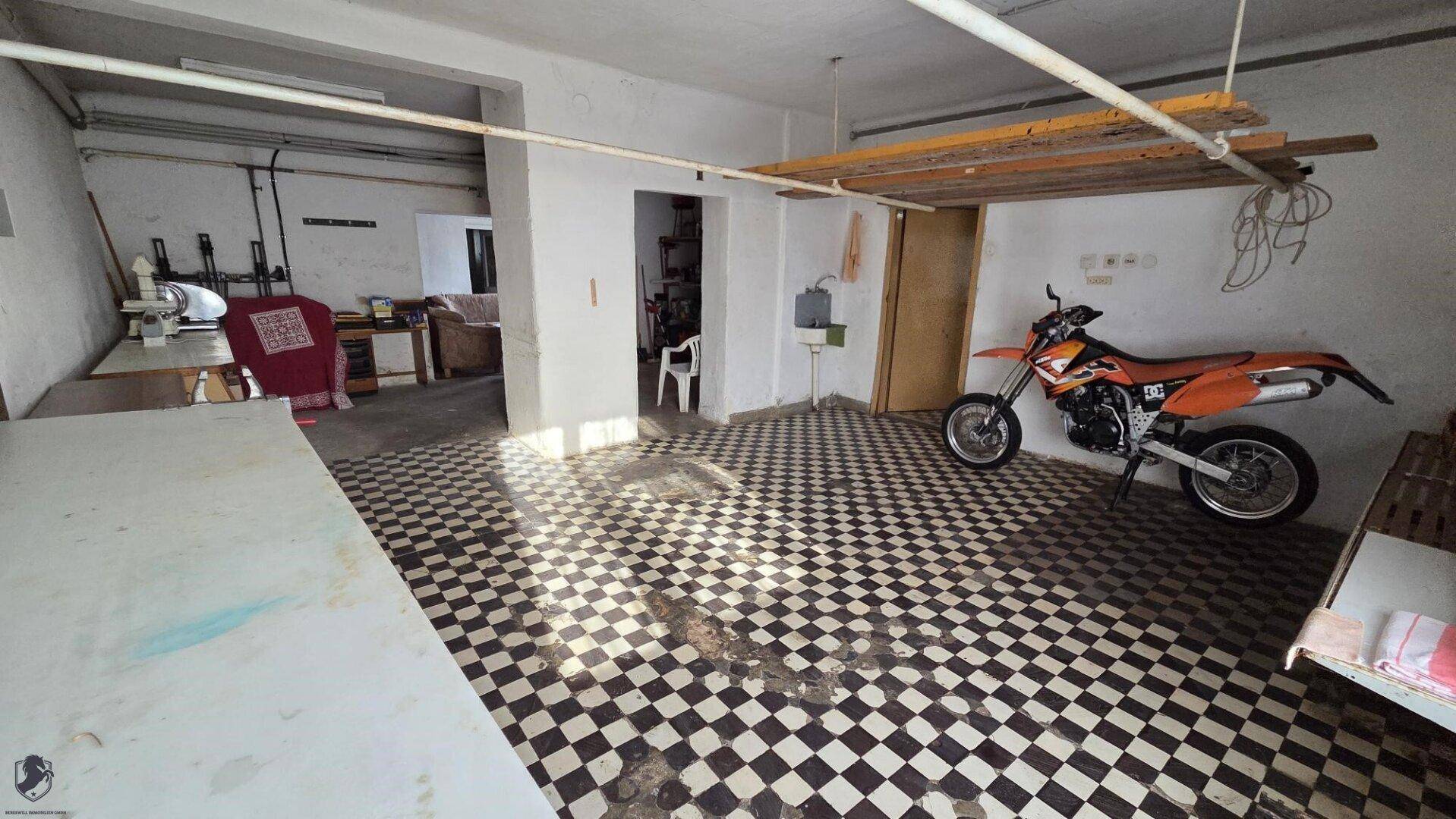 Geräumige Garage oder Werkstatt mit kariertem Boden und Motorrad.