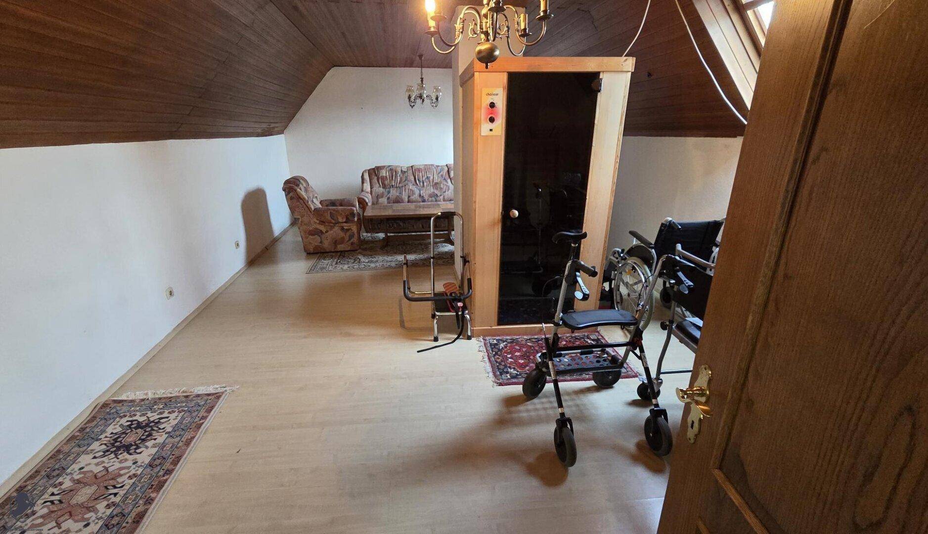 Ausgebauter Dachboden mit Holzdecke, kleiner Sauna und Sitzbereich.