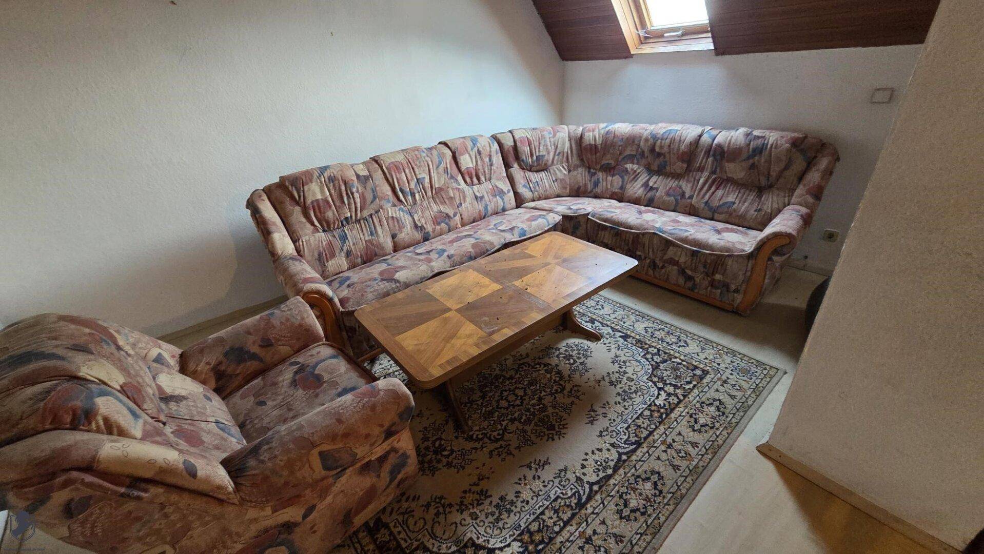 Gemütlicher Sitzbereich im Dachgeschoss mit großem Ecksofa und Teppich.