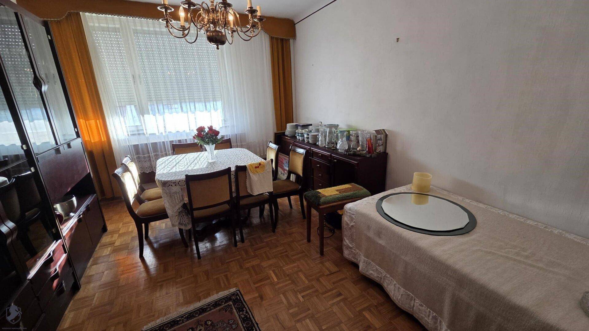 Klassisches Esszimmer mit großem Esstisch, Sideboard und Parkettboden.