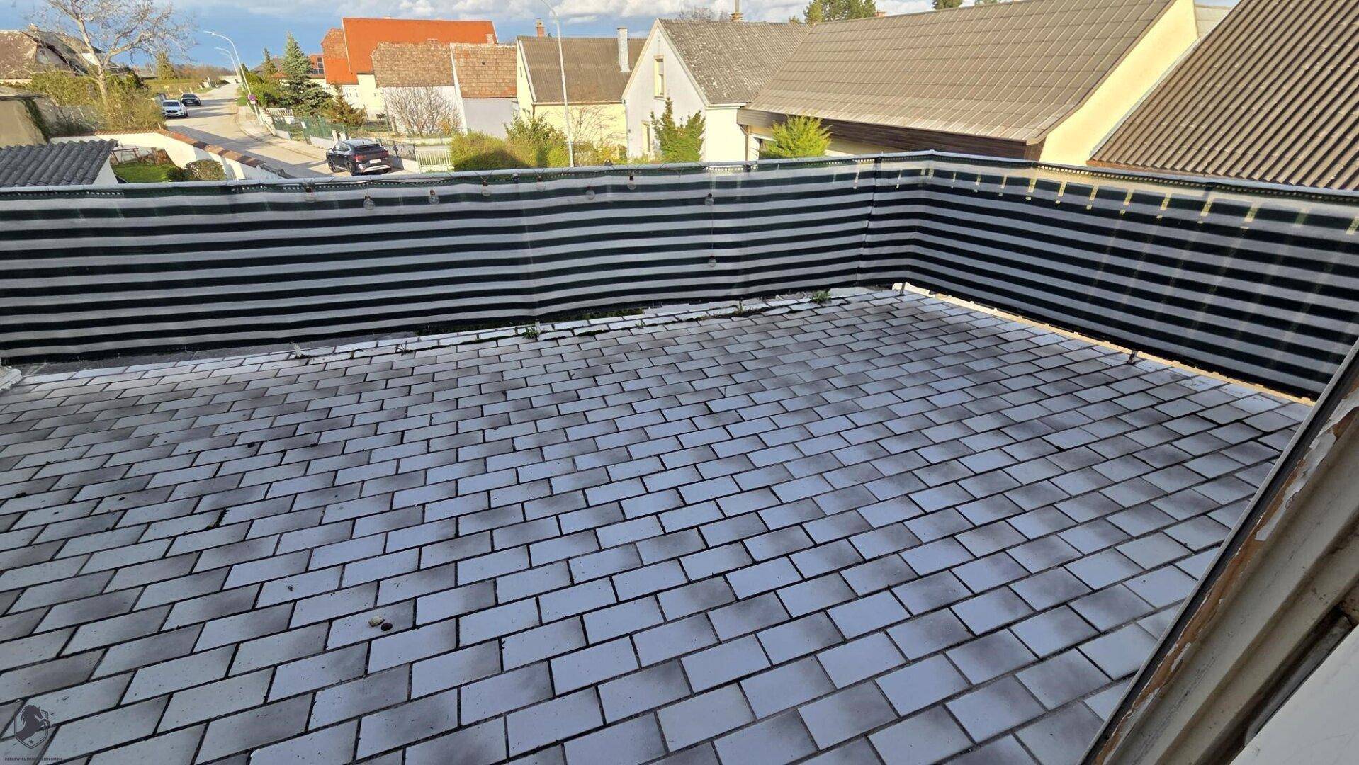 Geflieste Terrasse mit Sichtschutz und Blick auf die Nachbarschaft.
