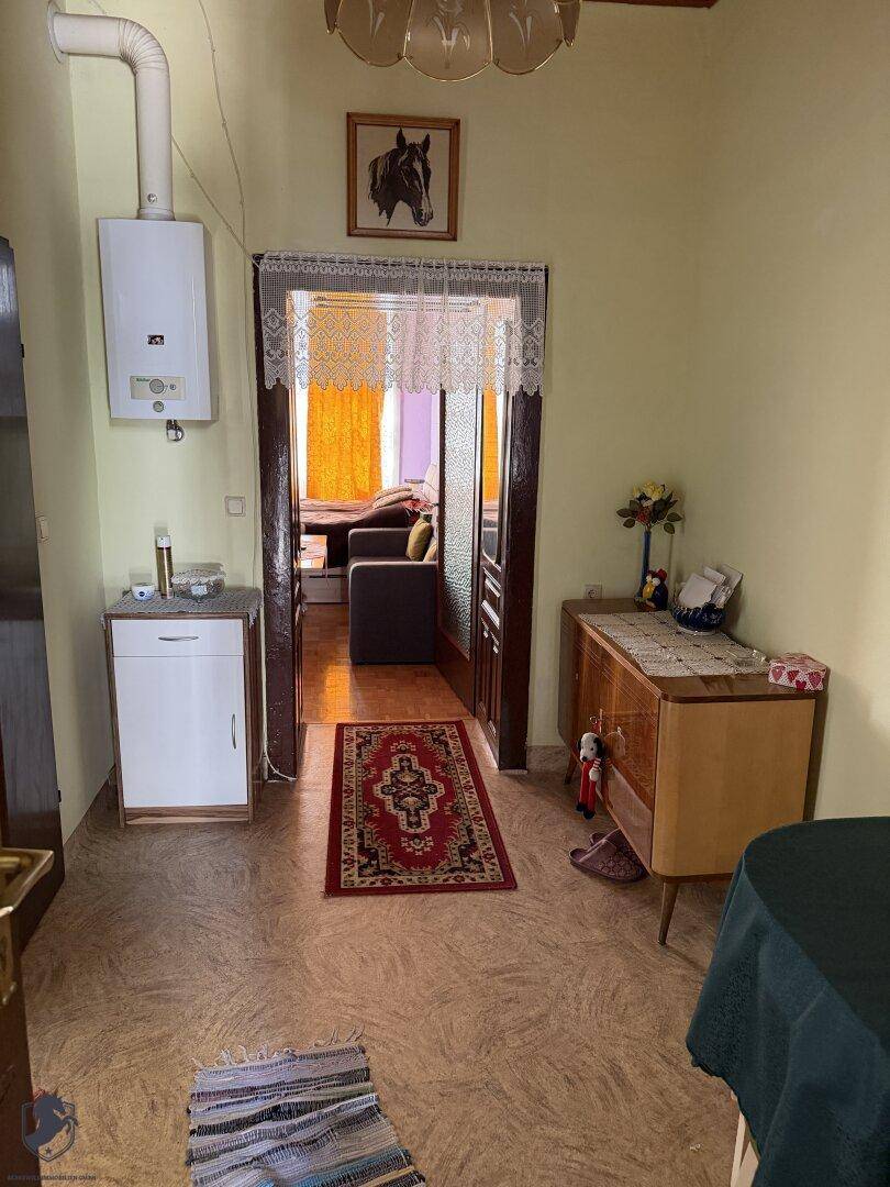 Eingangsbereich der Wohnung mit Gastherme, Linoleumboden und Blick in ein angrenzendes Zimmer.