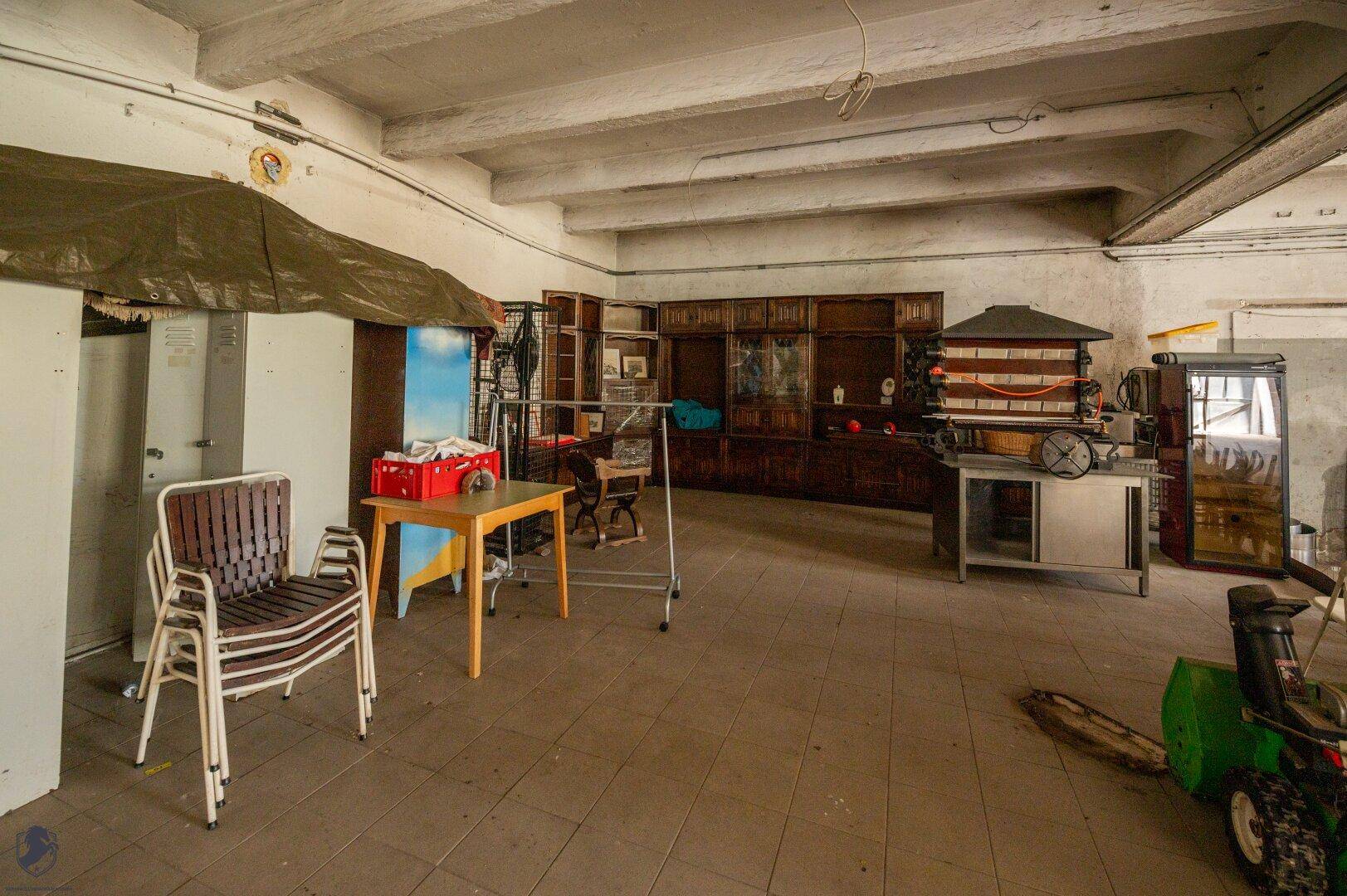 Großer, heller Industrieraum mit hohen Decken, Betonbalken und verschiedenen Maschinen und Lagerregalen.