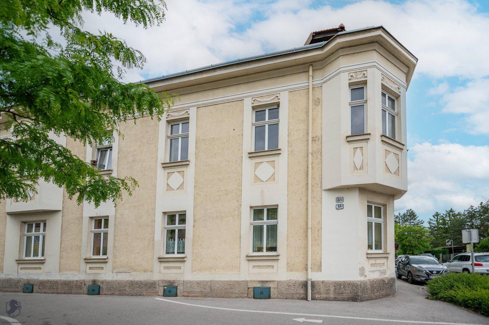 Detailansicht der historischen Fassade mit Erker und dekorativen Elementen unter bewölktem Himmel.