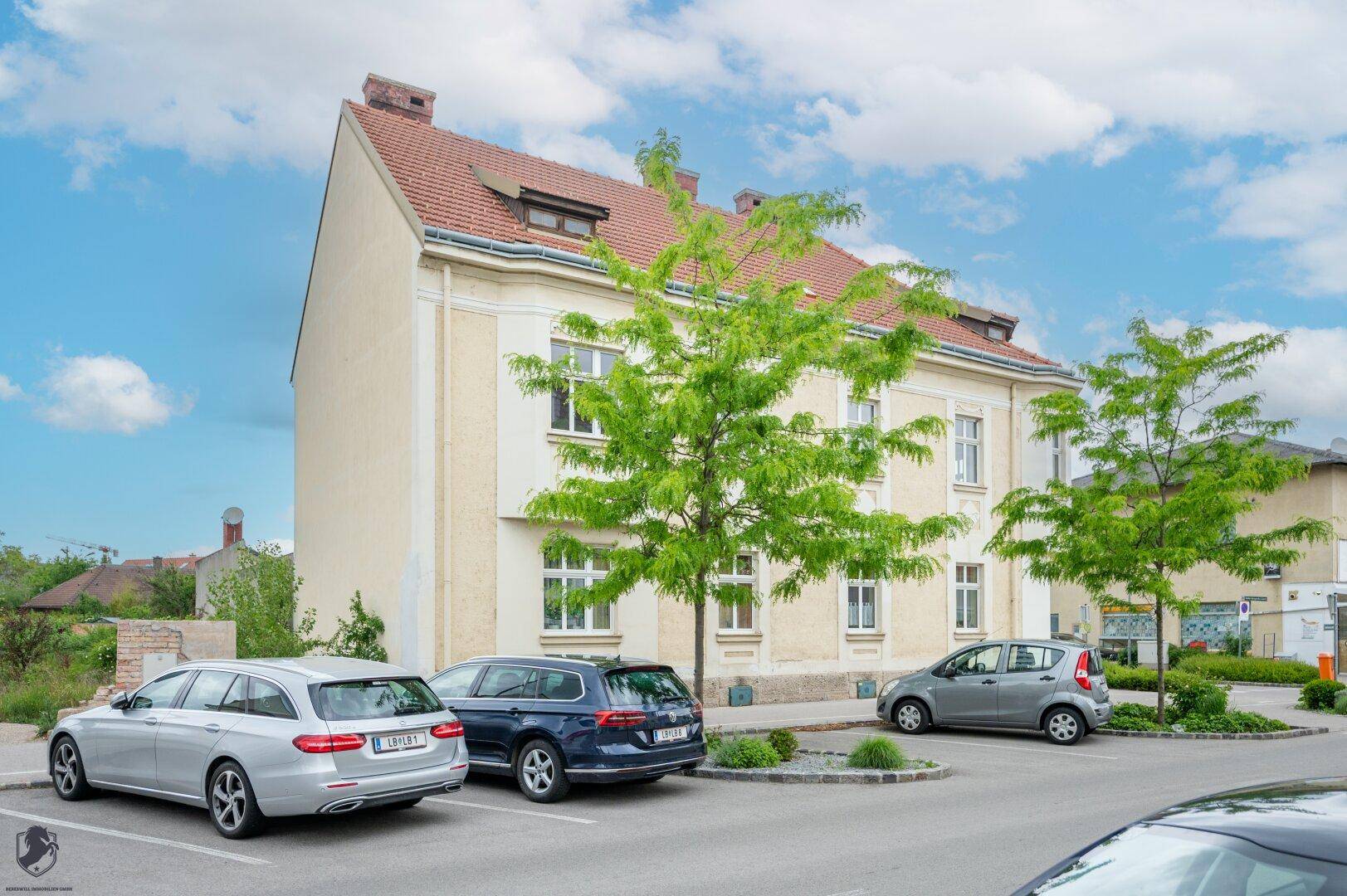 Seitenansicht des historischen Gebäudes mit Satteldach und geparkten Autos auf der Straße.