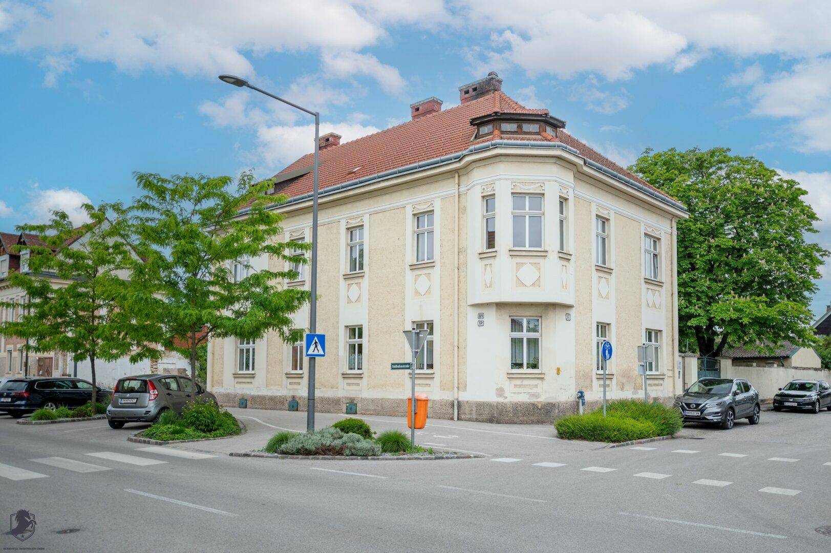 Historisches Eckgebäude mit klassischer Fassade und vielen Fenstern an einer städtischen Kreuzung.
