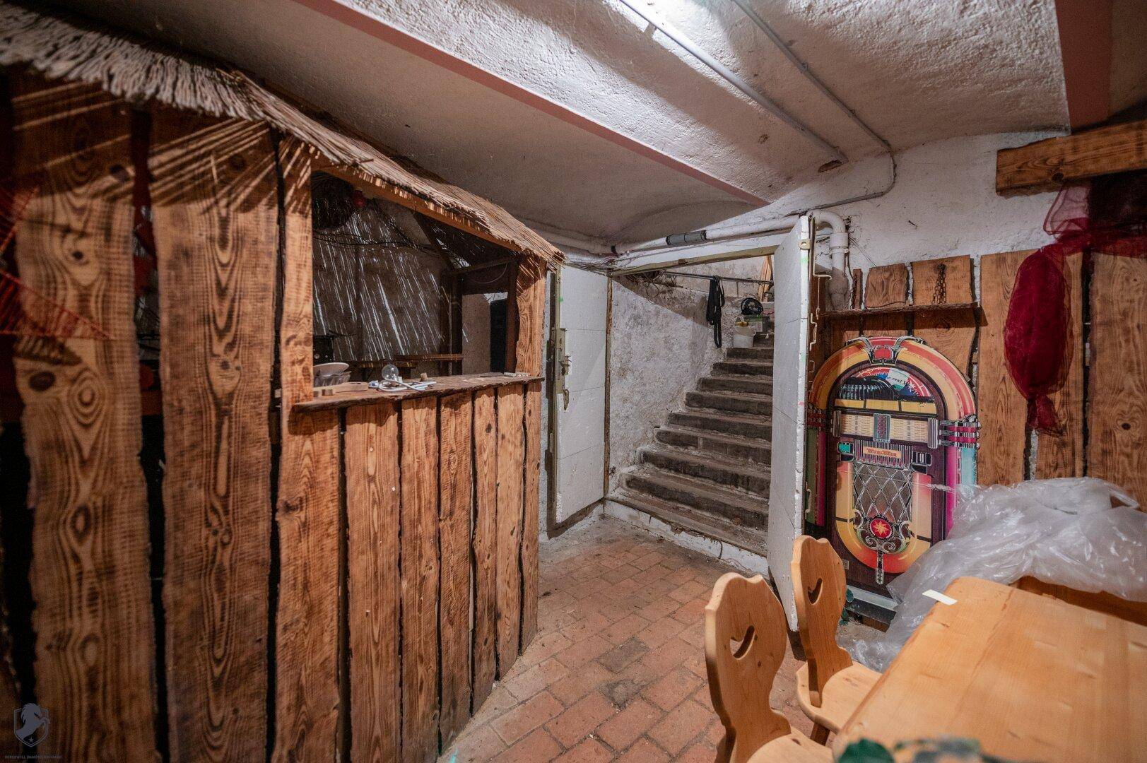 Kellerraum mit rustikaler Holzverkleidung und einer kleinen Bar, perfekt für Unterhaltung.