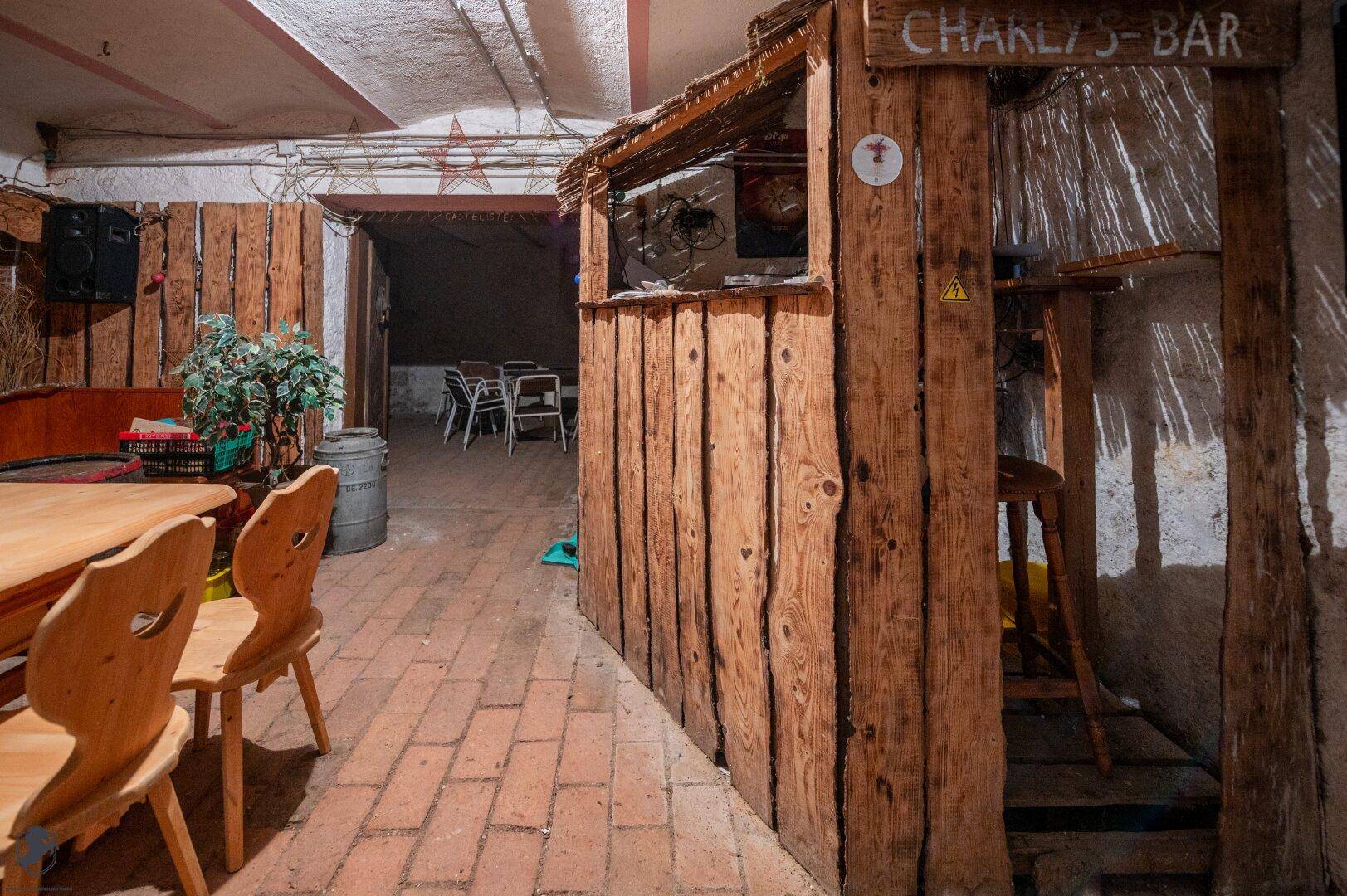 Kellerraum mit rustikaler Holzbar und Sitzgelegenheiten, ideal für private Feiern und Treffen.