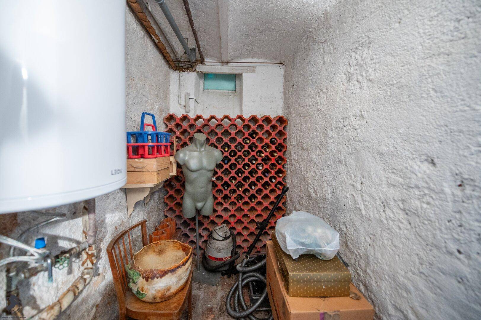 Kellerraum mit Weinregal, Warmwasserboiler und verschiedenen Lagergegenständen.