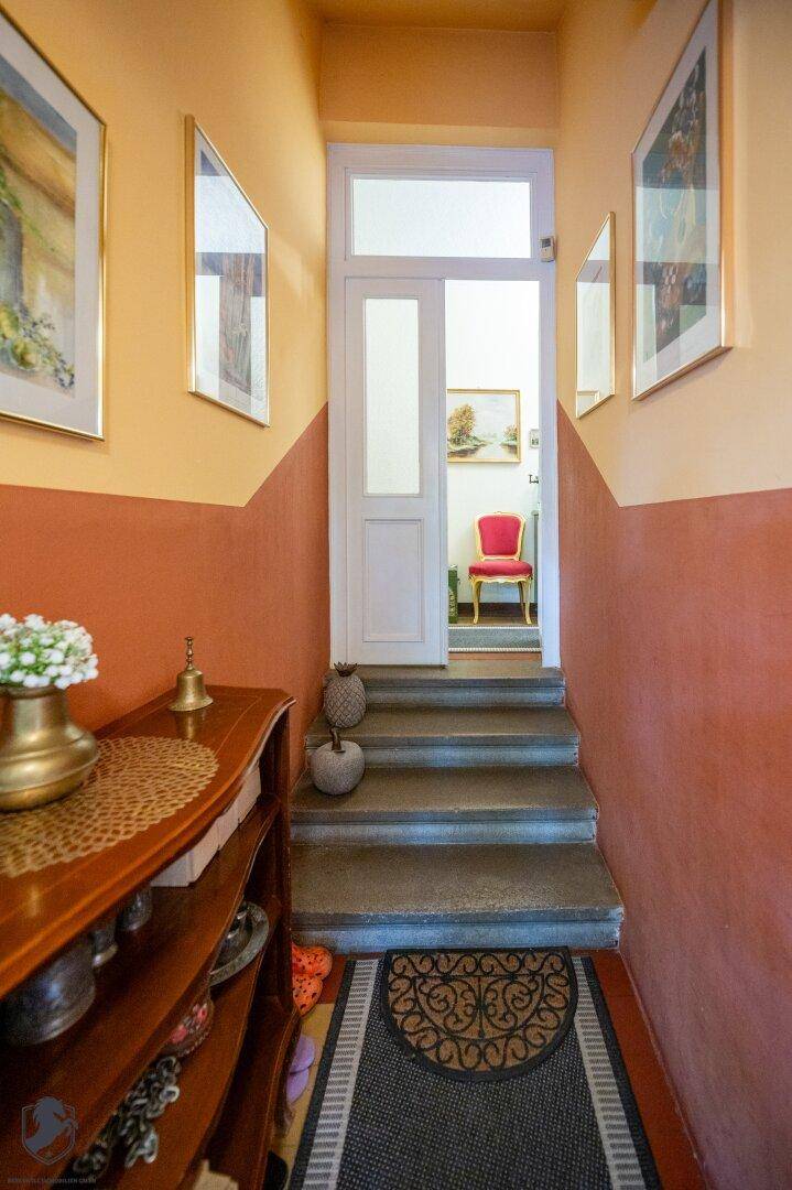 Eingangsbereich mit Steintreppe, farbigen Wänden und dekorativen Elementen.