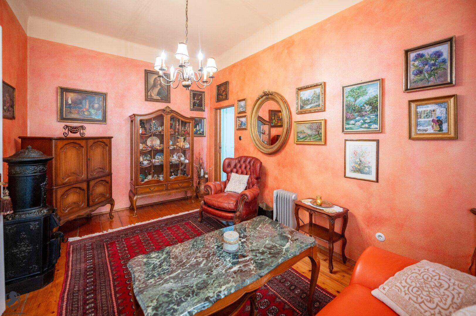 Traditionelles Wohnzimmer mit orangefarbenen Wänden, Holzboden und antikem Mobiliar.