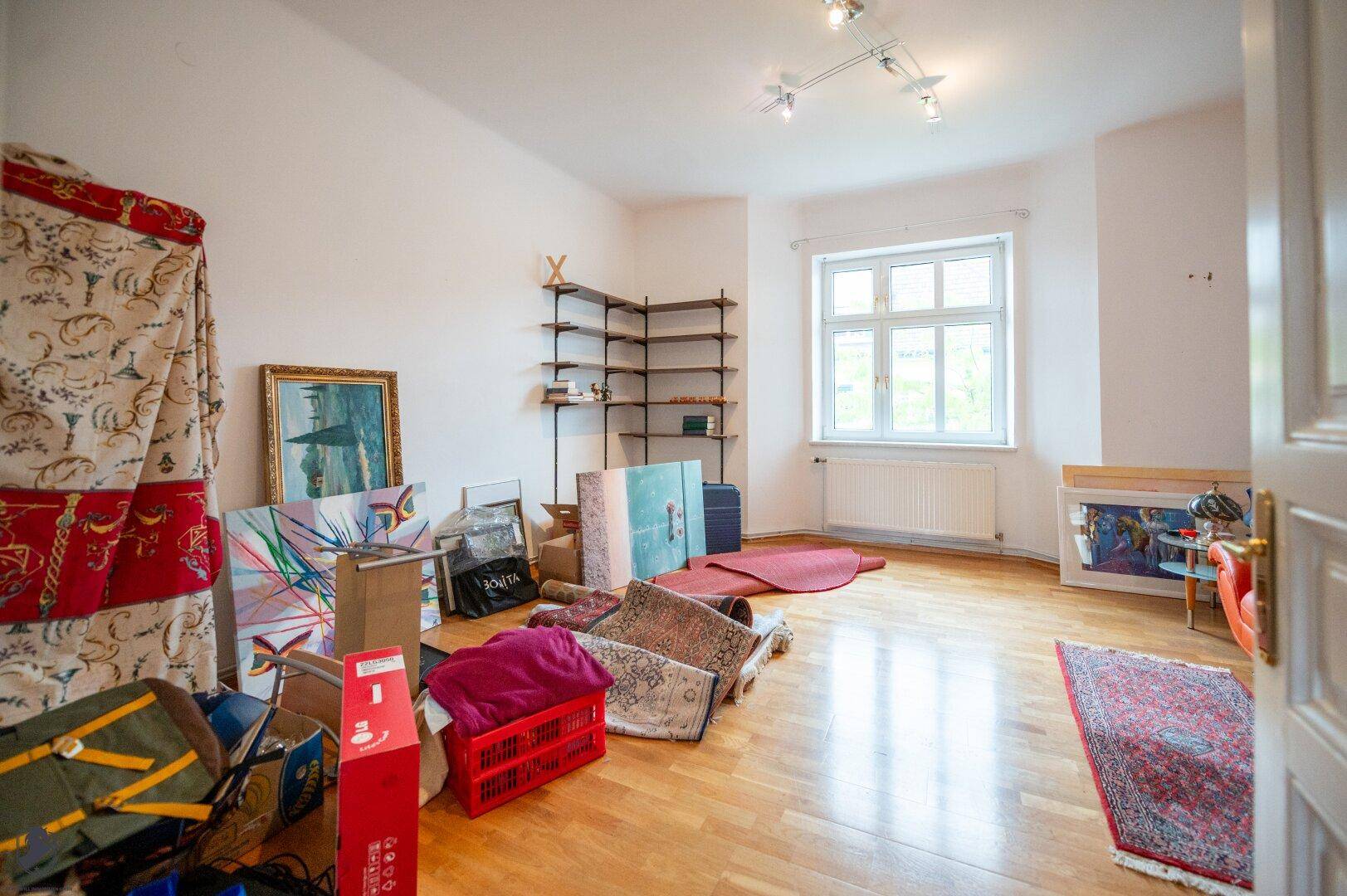 Geräumiges Zimmer mit Parkettboden und Fenster, das als Lagerraum dient.