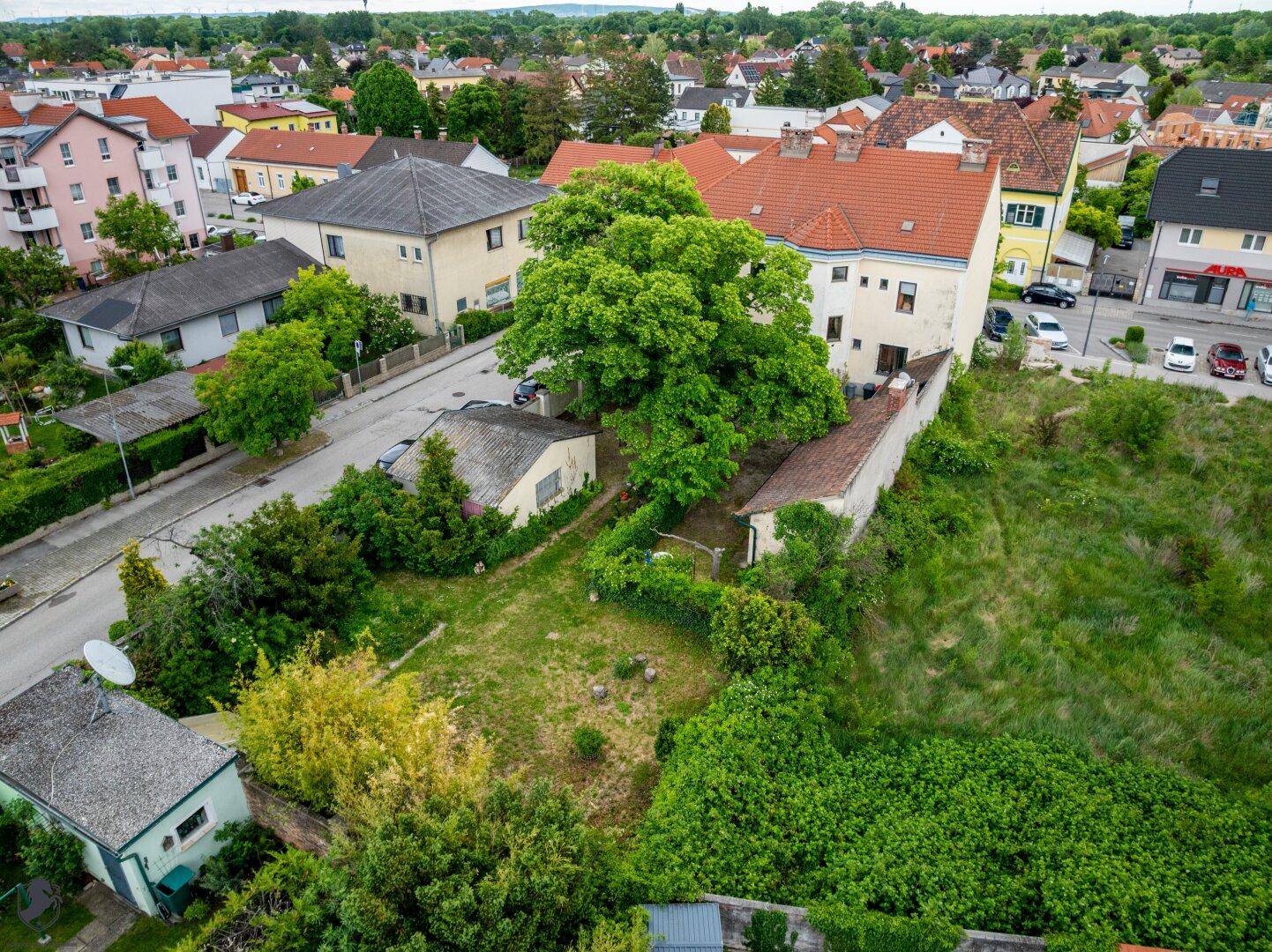 Luftaufnahme eines Wohngebiets mit Häusern, Straßen und viel Grünfläche.