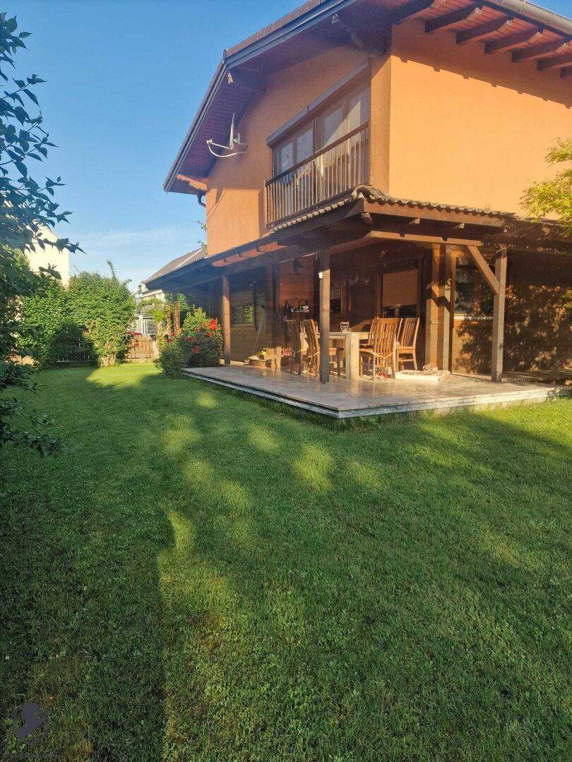 Weitläufiger Garten mit gepflegtem Rasen, überdachter Terrasse und dem Haus im Hintergrund.