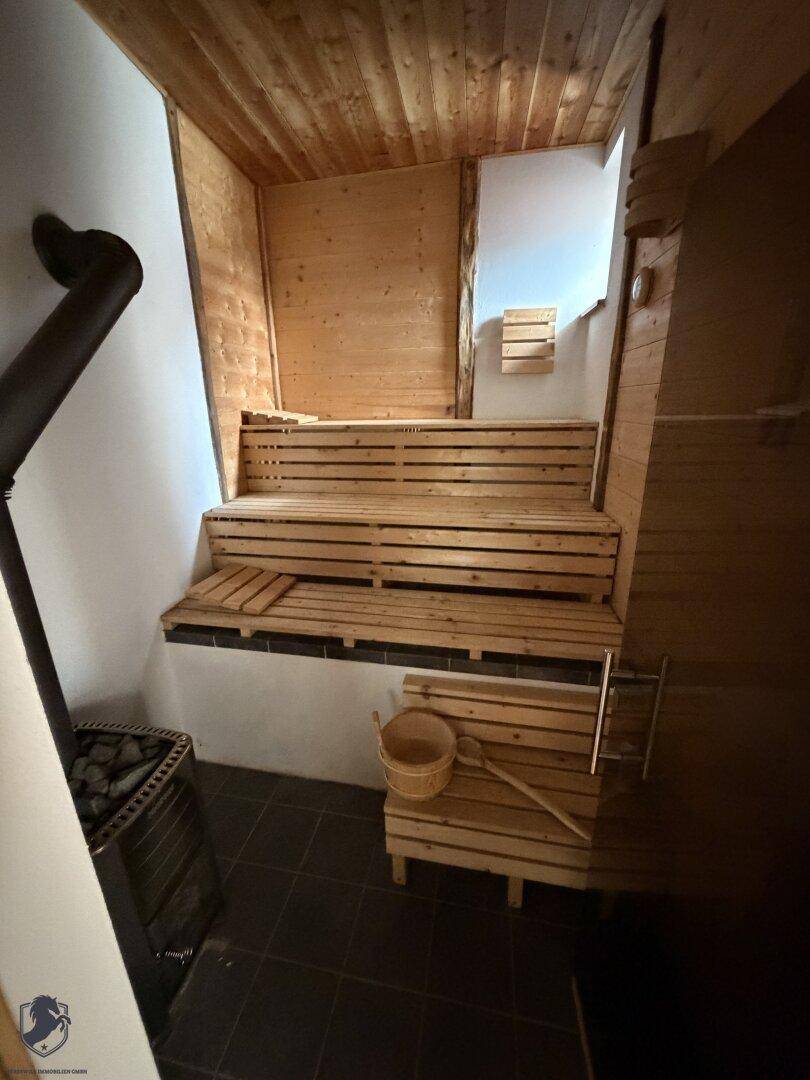 Gemütliche Holzsauna mit mehreren Bänken und einem Saunaofen, bereit zur Entspannung.