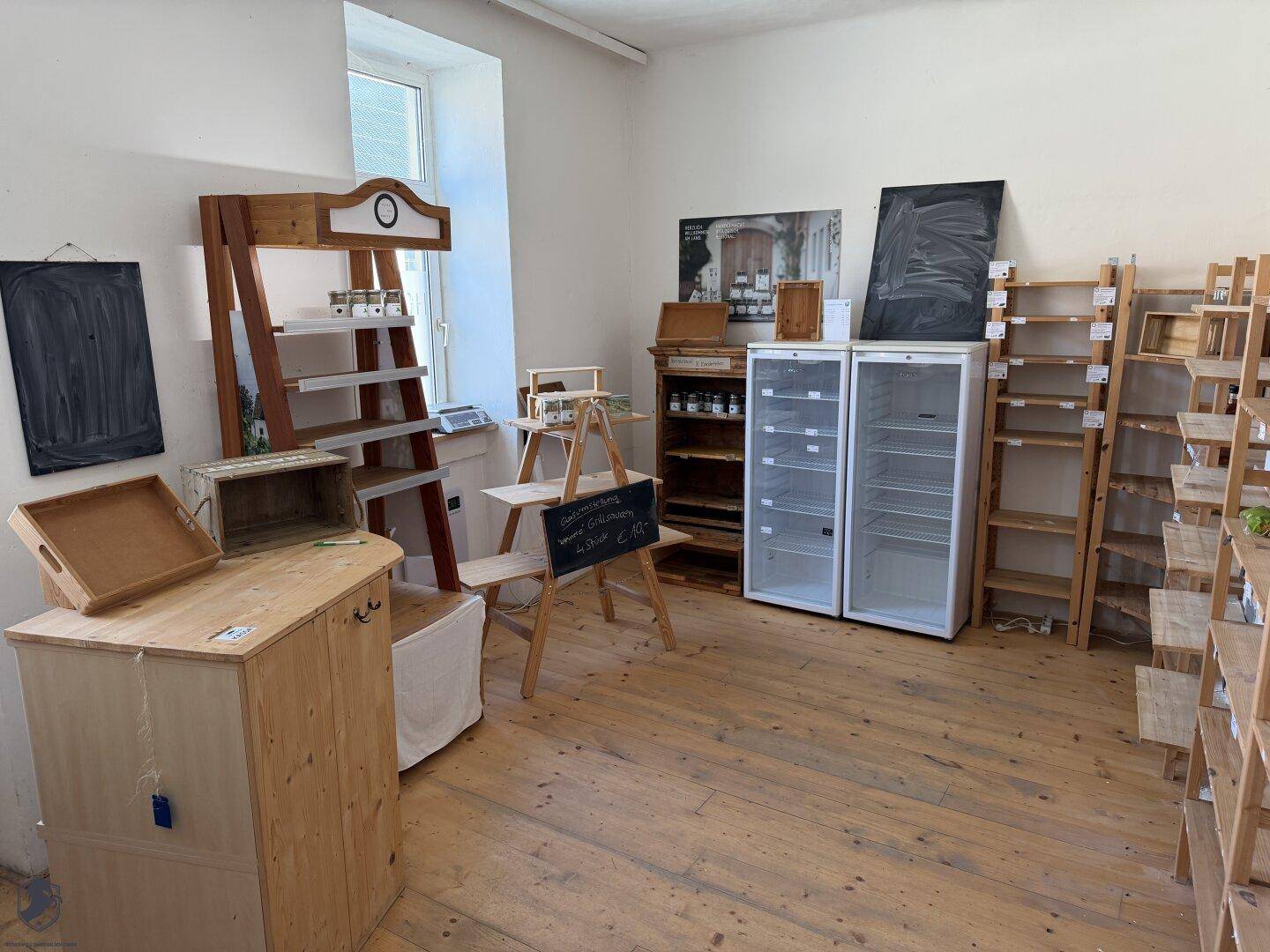 Großer Raum mit Holzdielenboden und verschiedenen Holzregalen, möglicherweise für einen Laden oder Marktstand.