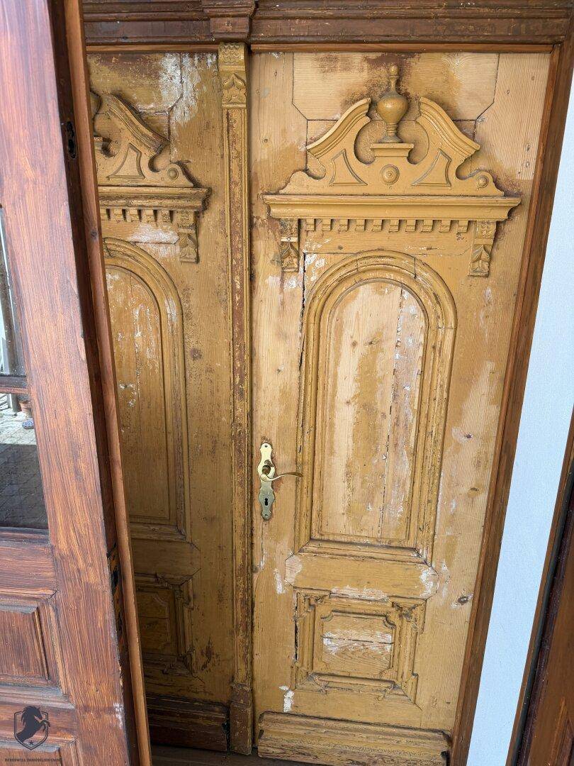 Alte, verzierte Holztüren mit abblätternder Farbe und traditionellen Beschlägen, die den Charme vergangener Zeiten zeigen.