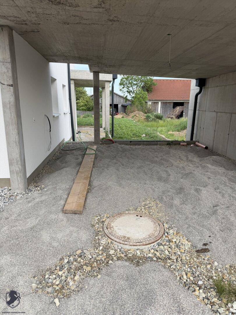 Unterbau eines Carports oder einer überdachten Terrasse mit Schotterboden im Rohbau.