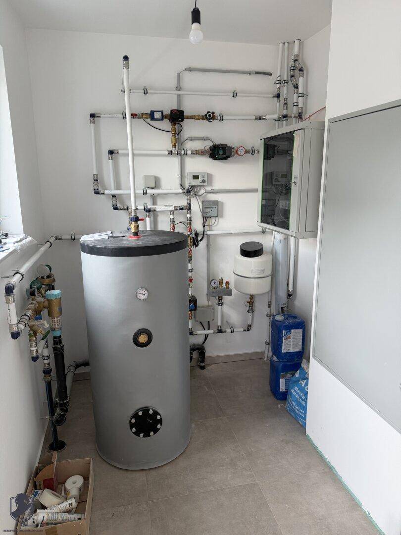 Hauswirtschaftsraum mit Warmwasserspeicher und komplexer Rohrinstallation im Neubau.