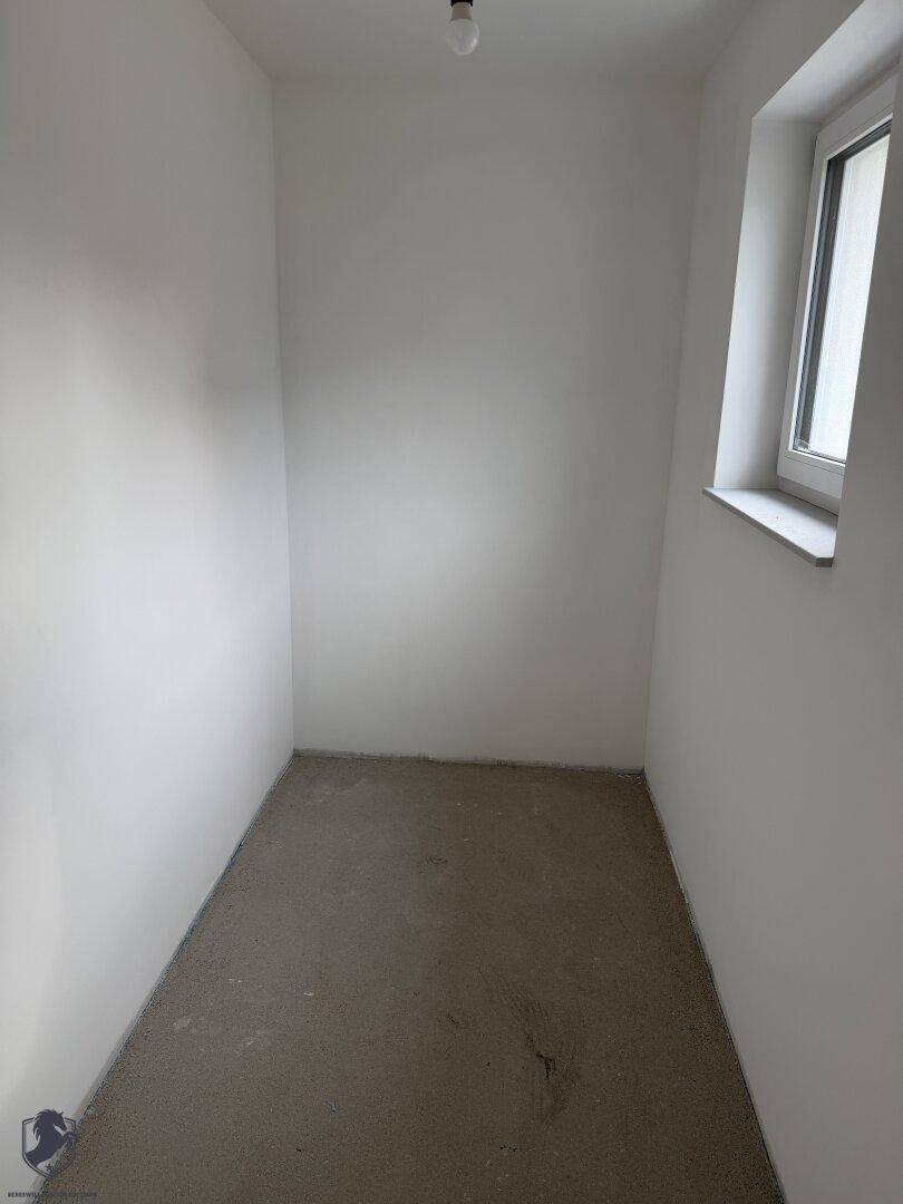 Kleiner Abstellraum im Rohbau mit Fenster und Rohbetonboden, ideal für Lagerzwecke.