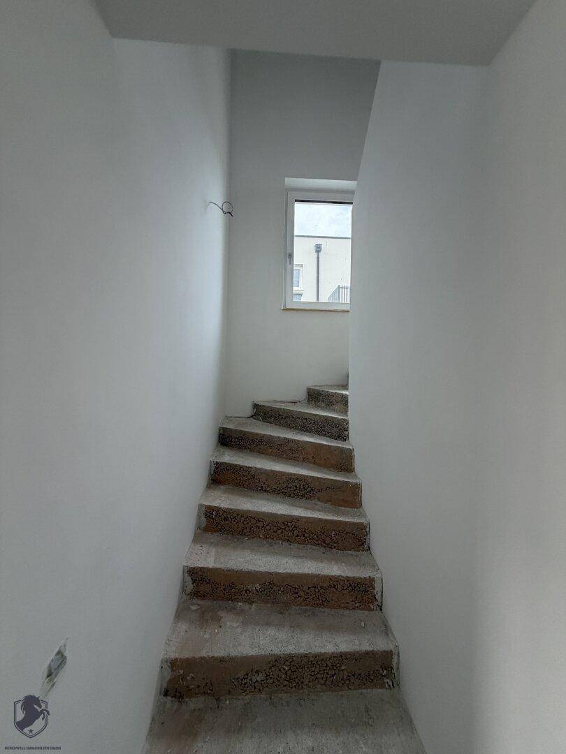 Unfertige Treppe im Rohbau mit Fenster, die die verschiedenen Etagen des Hauses verbindet.