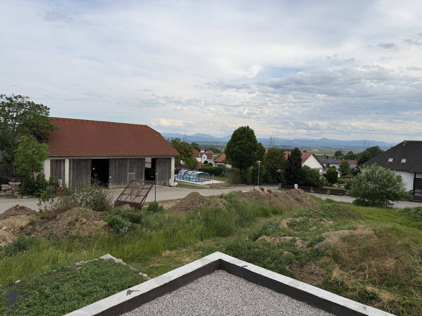 Weitblick von einem Flachdach über die Landschaft mit einem Pool in der Ferne.
