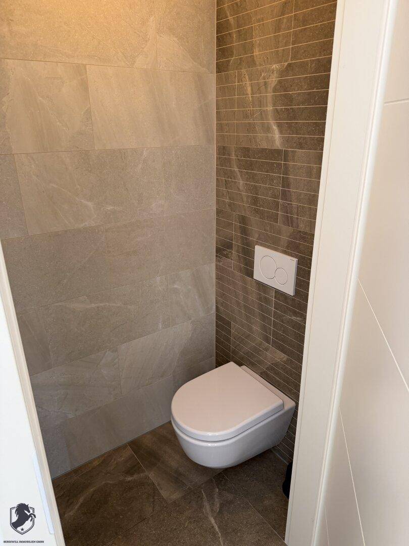 Separates Gäste-WC mit wandhängender Toilette und modernen Fliesen.