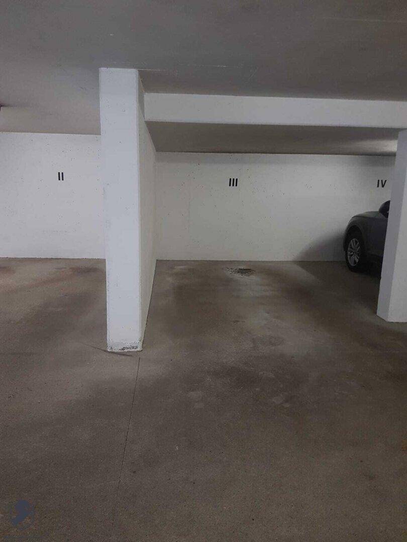 Weitere Ansicht der Tiefgarage mit leeren Stellplätzen und einer Säule in der Mitte.