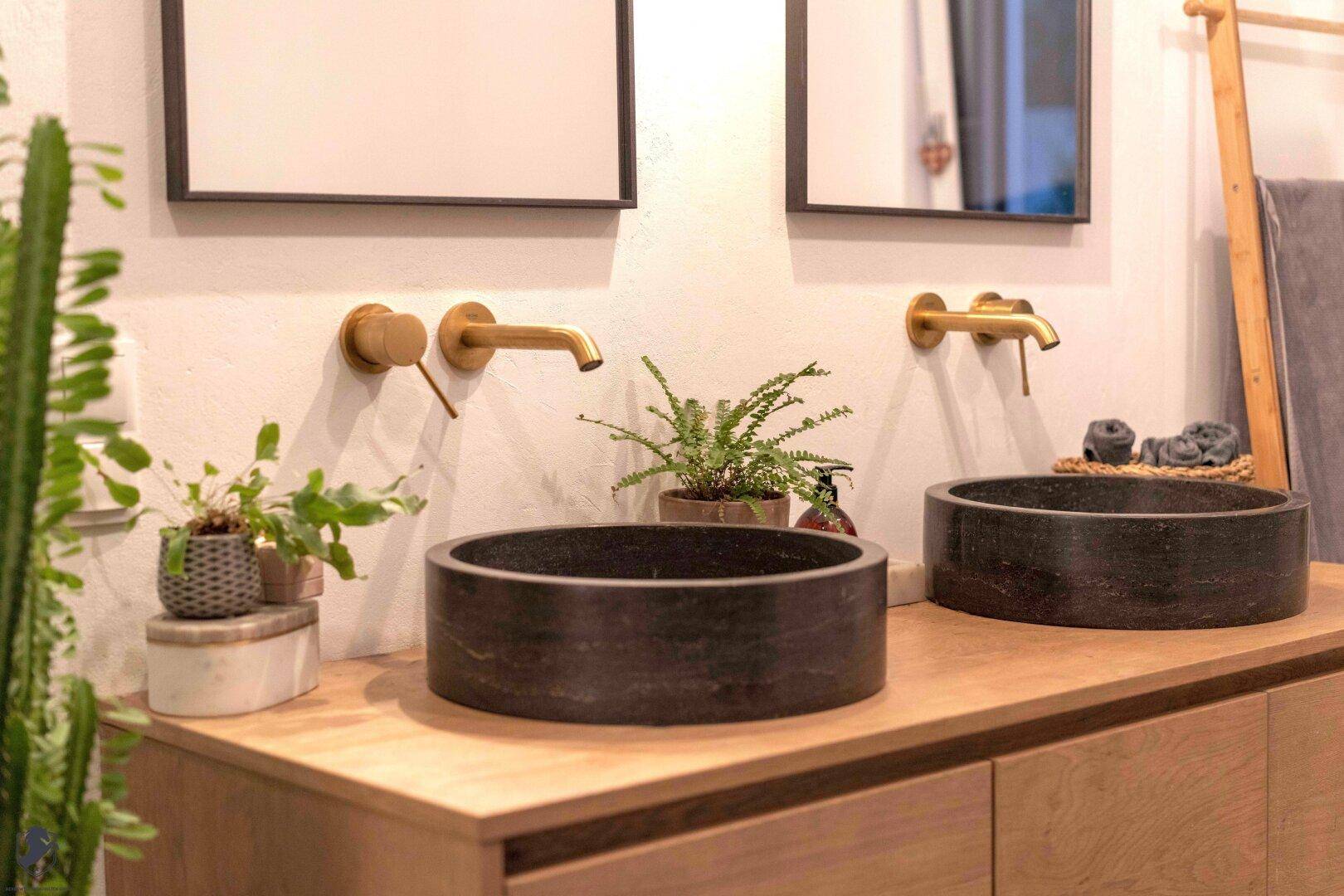 Modernes Badezimmer mit zwei runden Aufsatzwaschbecken und goldenen Armaturen.